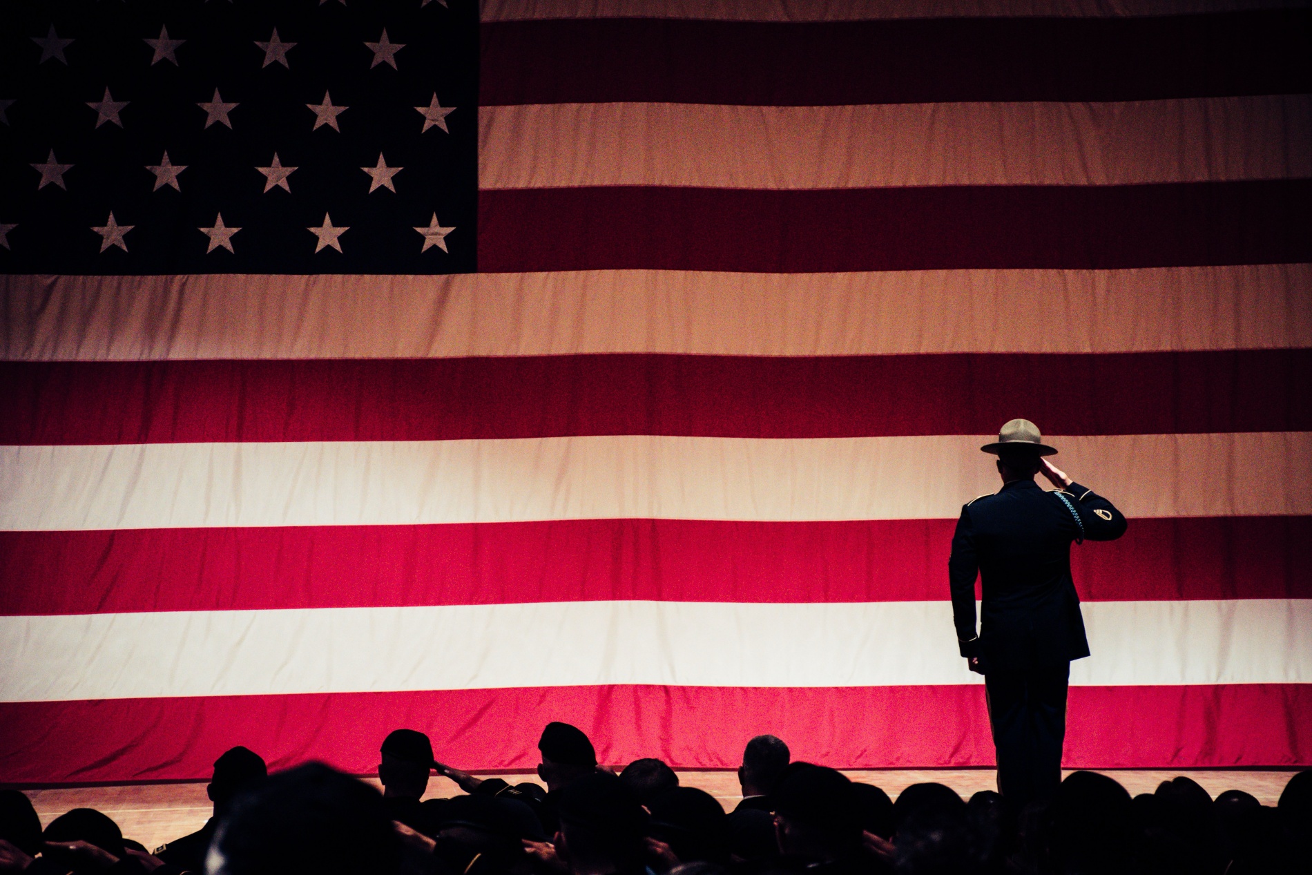 soldier saluting in front of a large US flag